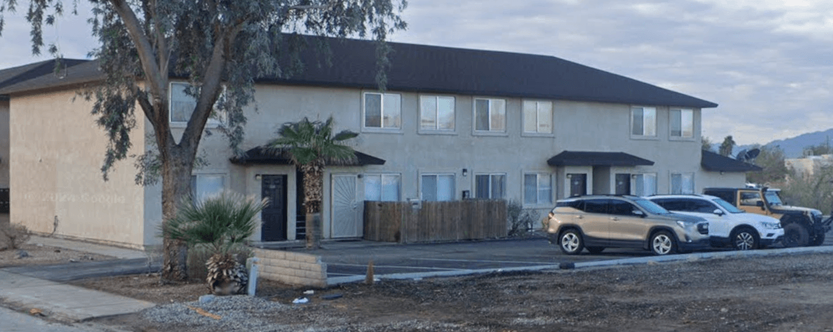 A house with a brown roof and a tree in front.